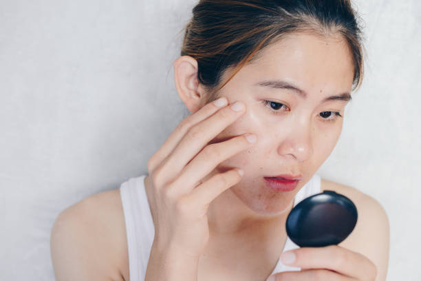 woman examining her face in a mirror